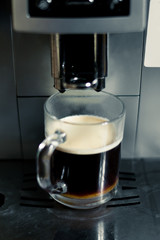 A cup of coffee in the coffee machine. The process of making coffee