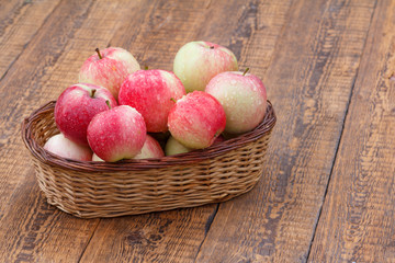 Red apples in the wicker basket on wooden boards