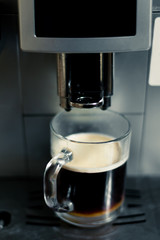 A cup of coffee in the coffee machine. The process of making coffee