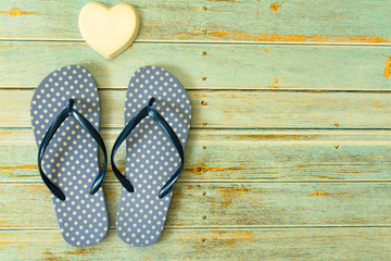 Blue flip flops and white porcelain heart on a wooden floor. Concept of holidays, vacations.