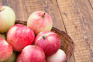 Red apples in the wicker basket on wooden boards