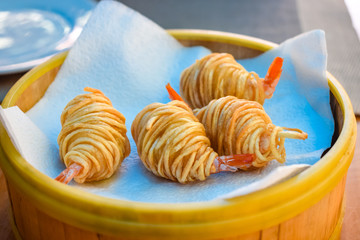 Fried potato wrapped shrimps on plate in restaurant