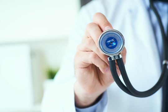 Close up of a doctor's hand, holding a stethoscope outstretched towards the viewer. Medic shop or store, physical and disease prevention, er consultant, 911, pulse measure, healthy lifestyle concept