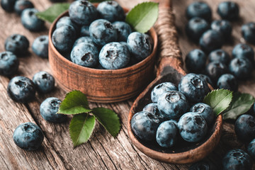 Blueberries in wooden spoon on old wood background. Healthy eating and nutrition concept.
