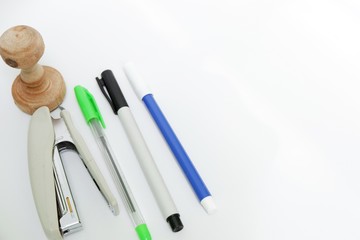 Pens,stamp and stapler isolated on white background. Top view close up details.
