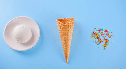 Vanilla ice cream with waffle cones and candy on the blue background