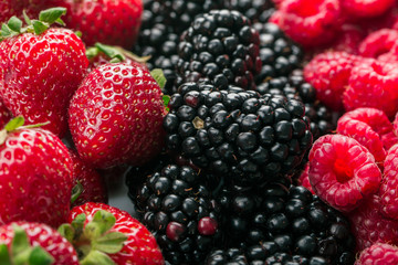 Fresh Summer berries mix with strawberries, raspberries and blackberry on wood background.
