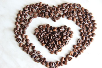 lots of heart-shaped coffee beans, background. coffee beans in the shape of a heart, after roasting on the table, selective focus.