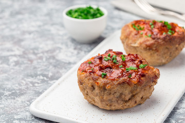 Low carb paleo meat cups, stuffed with champignons, bacon and cheese, garnished with green onion, on white plate, horizontal, copy space