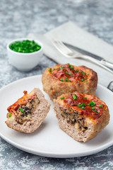 Low carb paleo meat cups, stuffed with champignons, bacon and cheese, garnished with green onion, on a white plate, vertical