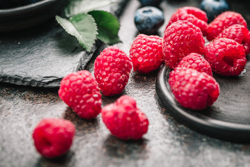 Freshly picked raspberries in bowl on old metal background. Healthy eating and nutrition.