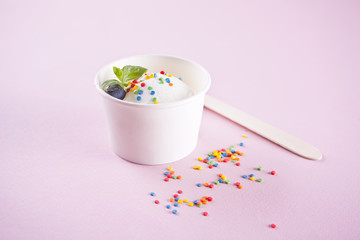 Vanilla ice cream with mint leaf and colorful candy on the pink background