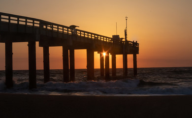 Fototapeta na wymiar Sunrise at St. Augustine Beach Pier with silhoutted fisherman