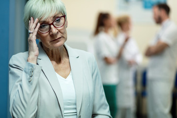 Worried mature woman thinking in hospital lobby.