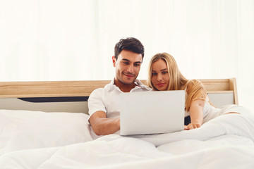 Couple caucasian lover smiling enjoy using laptop computer together on bed early morning