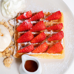 Top angle view of closeup strawberry waffle with honey for topping