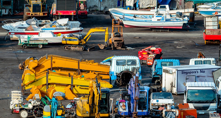 Heavy machinery second hand market. Boat, forklift, agricultural machinery, and electric generator on dirty concrete floor. Warehouse of heavy machinery for manufacturing factory.