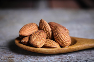 Almond nuts in wooden spoon on rustic background.