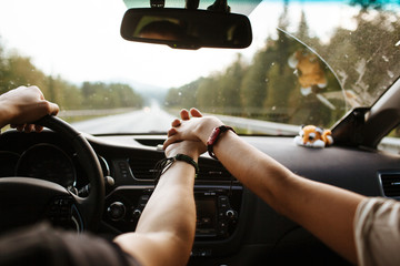 The guy with the girl in the car holding hands while driving on the road