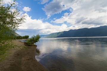 The shore of Lake Teletskoye in Altai mountains. Beautiful summer landscape. Rain drops on water.