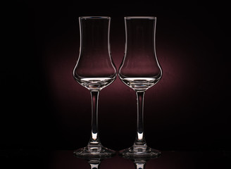 Two glasses of cognac sniffer on a colored dark background