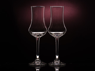 Two glasses of cognac sniffer on a colored dark background