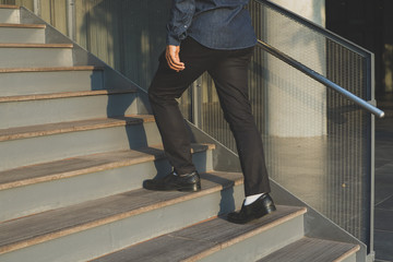 Businessman legs walking up the stairs.