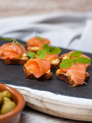 Smoked salmon on toast with butter with mint leaf on black stone and old wooden board - Image