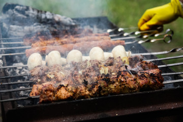  man's hand turns the barbecue on the grill