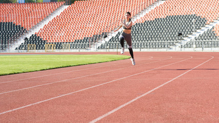 Fototapeta premium Beautiful athletic girl running around the stadium