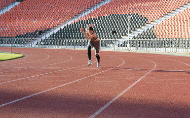 Beautiful athletic girl running around the stadium