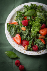 Vitamin salad with kale salad, basil, strawberry, raspberry and nuts