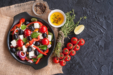 Greek salad with cucumber, tomato, pepper, salad, onion, feta cheese and olives, dressed with olive oil on a canvas napkin. The view from the top. Copy space.