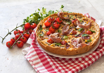 Tart or quiche with bacon, green beans, tomatoes and cheese on a red checkered tablecloth. French cuisine. The view from the top. Copy space.