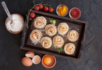 Asian dumplings in the shape of a rose flower. Ingredients for modeling homemade dumplings. Eggs, spices, flour, salt, pepper, meat. Dumplings on the cutting Board. Black background, top view.