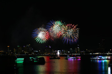 blur green red gold fireworks on beach and reflection color on water surface