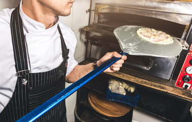 Professional chef cooking in the kitchen restaurant at the hotel, preparing dinner. A cook in an apron makes a salad of vegetables and pizza.