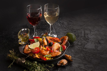 Paella on a pan with shrimp, mussels and wine on a black table. Spanish Mediterranean cuisine. Seafood is a healthy food concept. Copy space. - 269870412