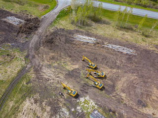 Aerial view of the four yellow crawler excavators that stand on the ground near the construction...