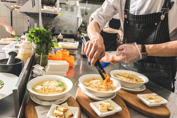 Professional chef cooking in the kitchen restaurant at the hotel, preparing dinner. A cook in an apron makes a salad of vegetables and pizza.
