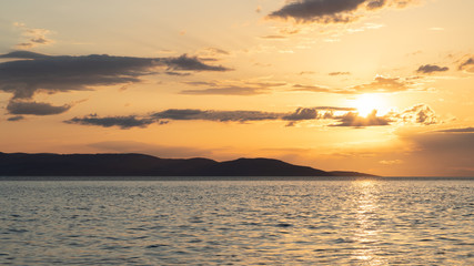 Sunset over the sea with an isle in the background