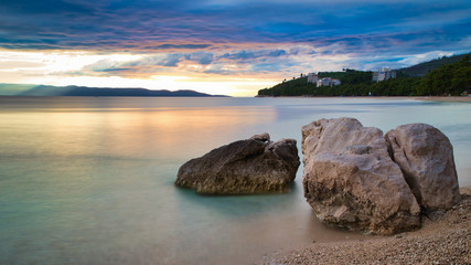 A romantic beach with rocks at sunset