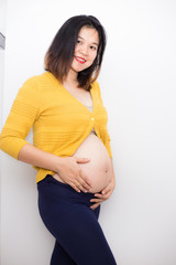 Joyful smiling pregnant women standing on white background