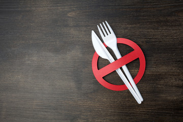 White plastic tableware on a wooden background as a symbol of environmental pollution. Ban single...