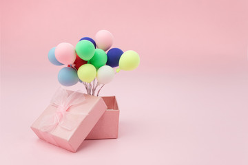 Pink gift box with colorful balloon on pink background. minimal hollyday concept.