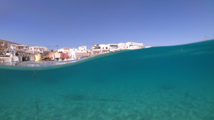 Underwater sea level photo of idilic pebble beach of Karavostasis, picturesque port of Folegandros island with traditional fishing boats docked and crystal clear turquoise sea, Cyclades, Greece
