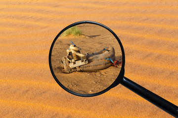 saddle for camel on the sand, view through a magnifying glass against the background of sand