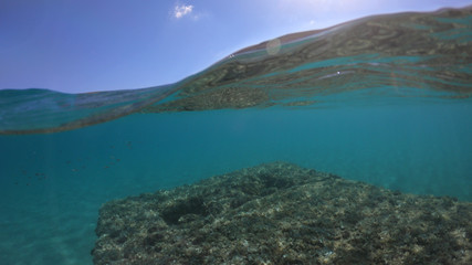 Fototapeta premium Underwater sea level photo of idilic pebble beach of Karavostasis, picturesque port of Folegandros island with traditional fishing boats docked and crystal clear turquoise sea, Cyclades, Greece