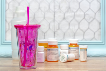 Pink Water Glass with Medicine Pill Bottles in Background
