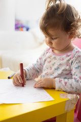 toddler girl drawing with crayons on paper